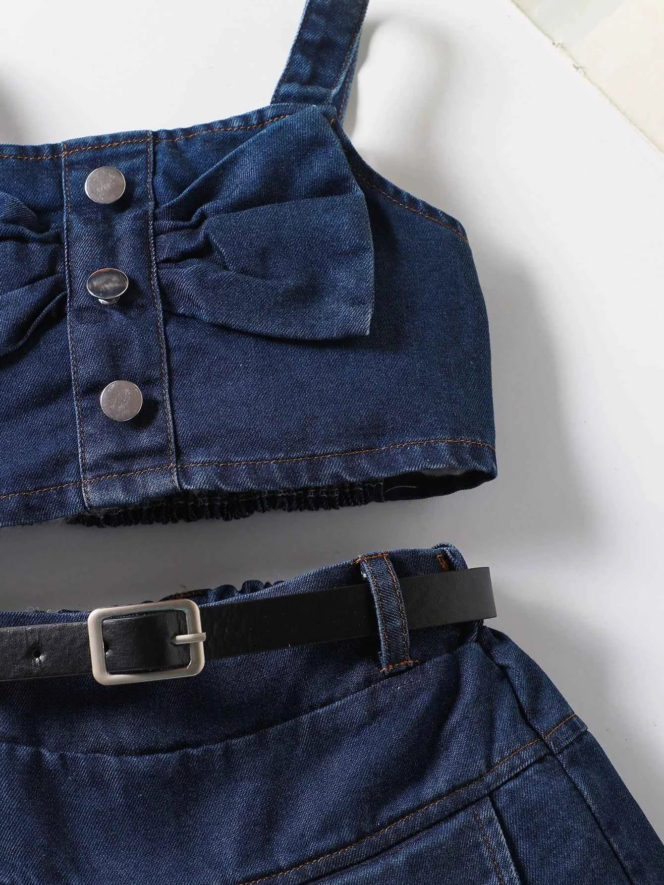The girl-loved denim pleated skirt set features a bow blouse with an attached belt.