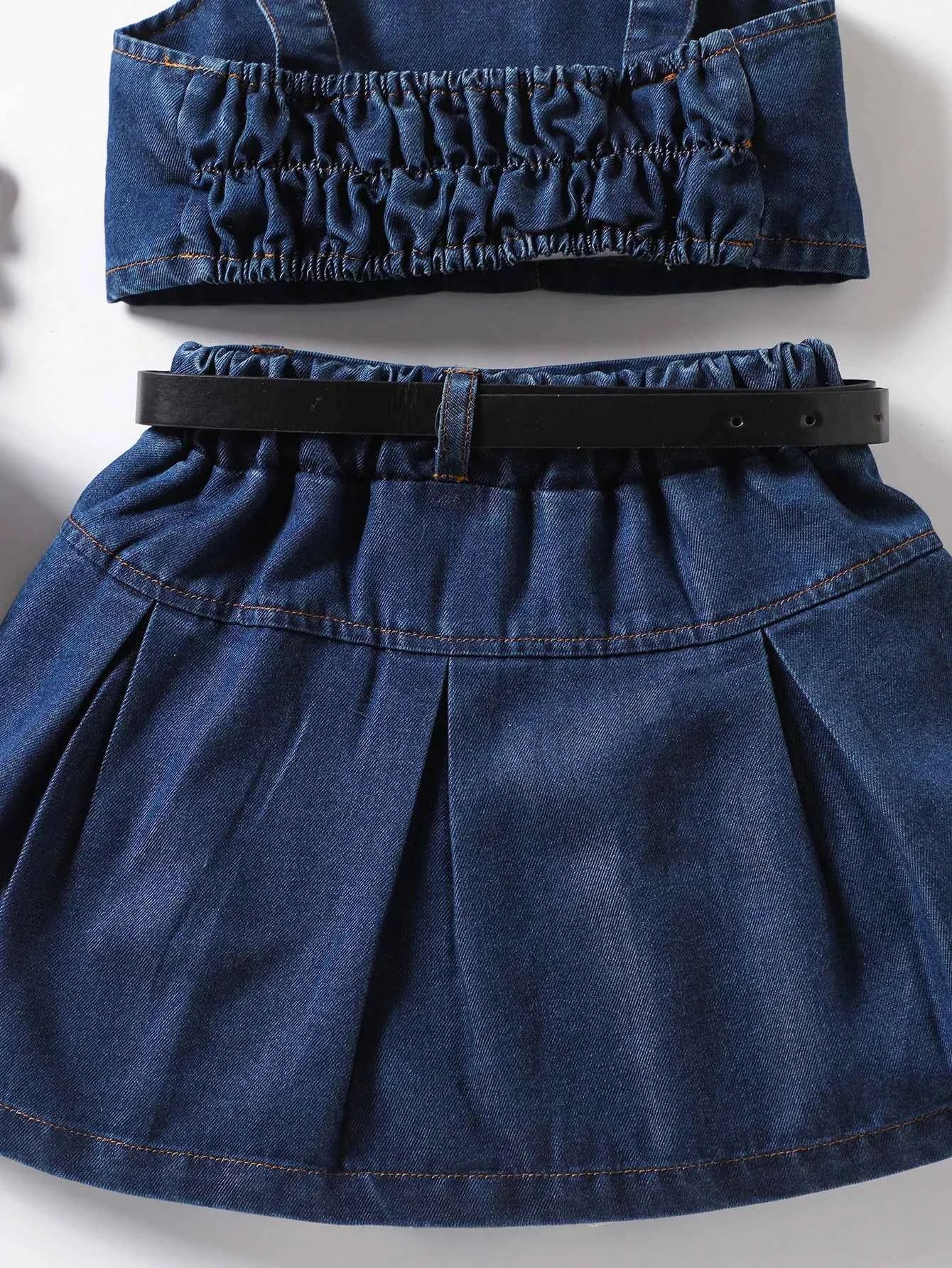 The girl-loved denim pleated skirt set features a bow blouse with an attached belt.